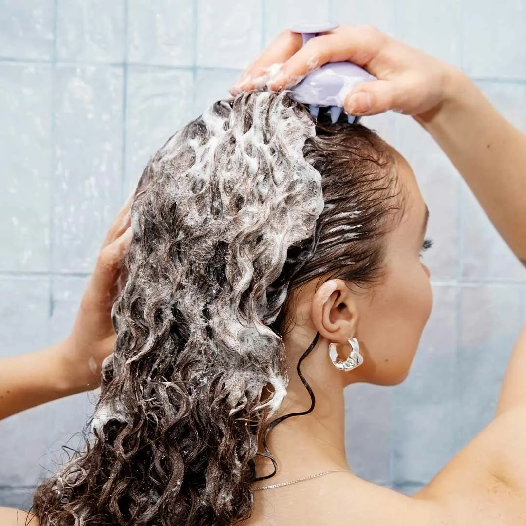Frau in Dusche massiert Kopfhaut mit Kopfhaut Massagebürste