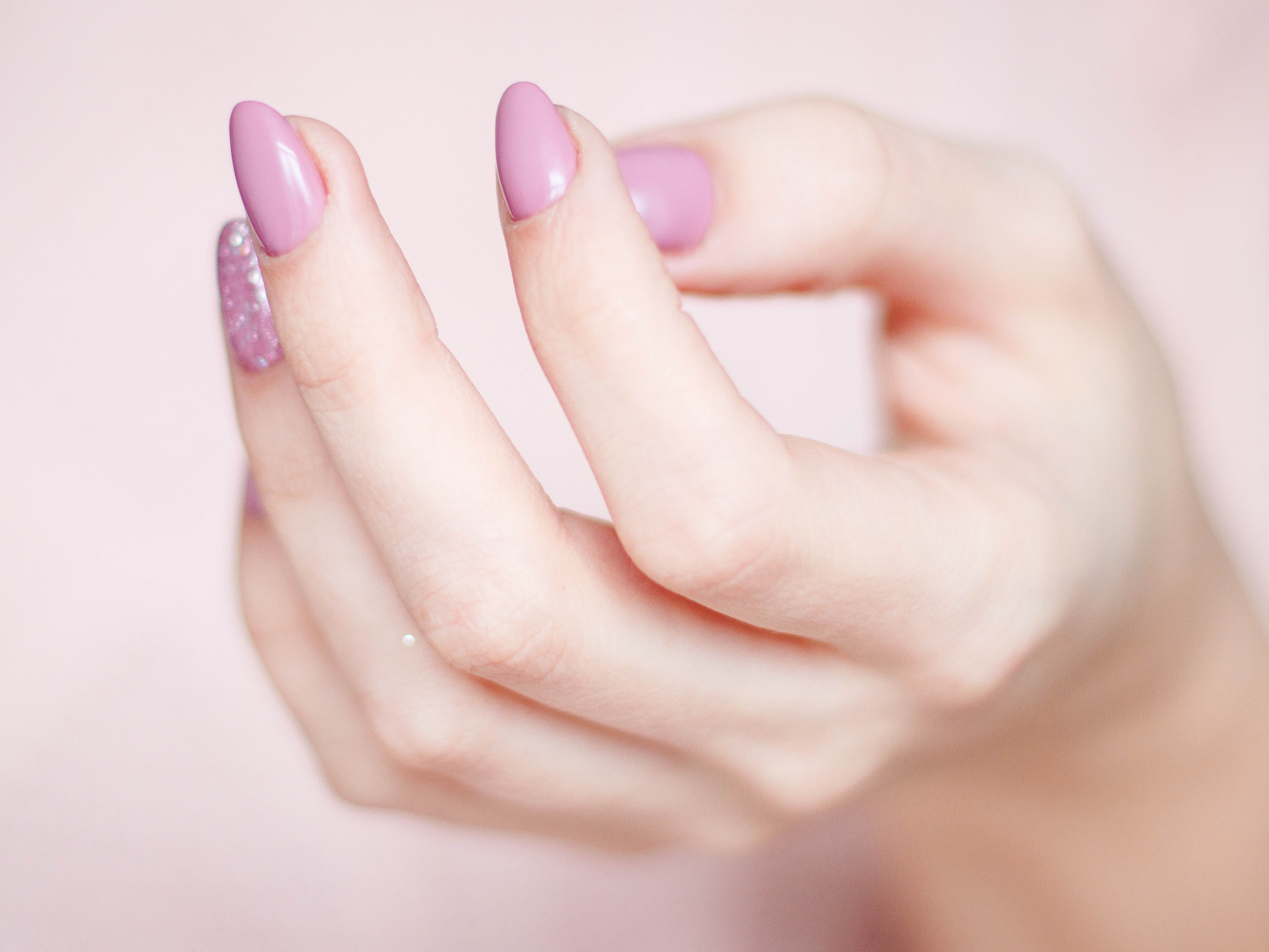 Hand mit zartrosa lackierten Fingernägeln